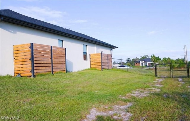 exterior space with a gate, a yard, fence, and stucco siding