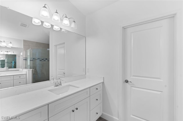 bathroom featuring visible vents, baseboards, two vanities, a stall shower, and a sink