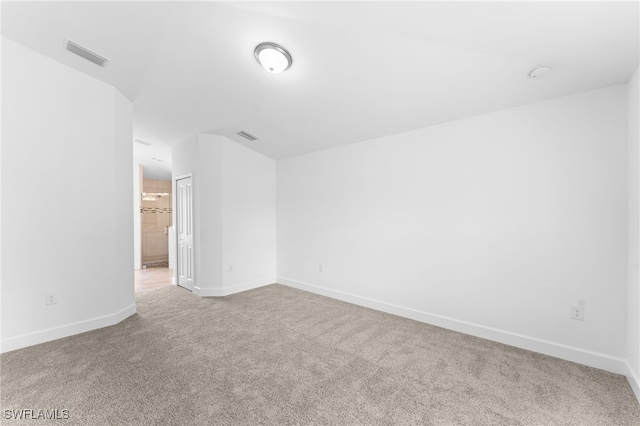 carpeted spare room featuring baseboards and visible vents