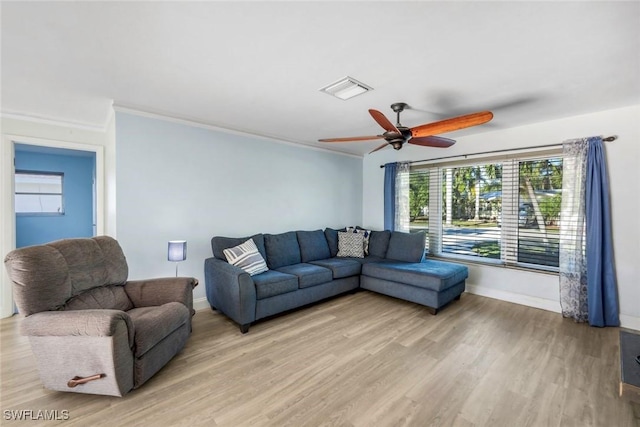 living area with a wealth of natural light, visible vents, a ceiling fan, and light wood finished floors