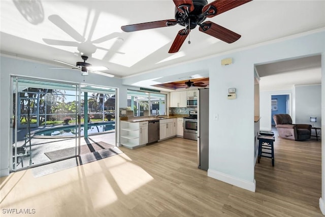 kitchen with crown molding, stainless steel appliances, white cabinetry, a ceiling fan, and a sink