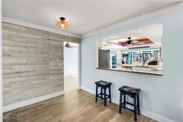 kitchen featuring a sink, wood finished floors, stainless steel appliances, wooden walls, and ceiling fan