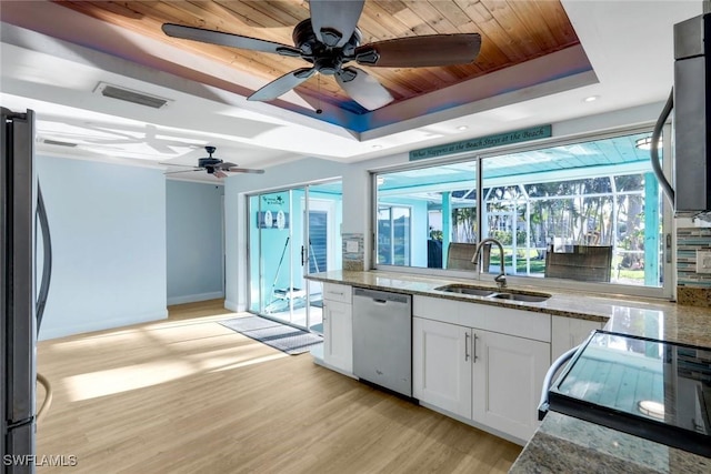 kitchen featuring visible vents, appliances with stainless steel finishes, white cabinetry, a raised ceiling, and a sink