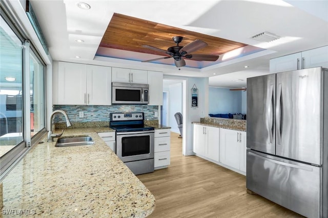 kitchen with visible vents, appliances with stainless steel finishes, a tray ceiling, and a sink