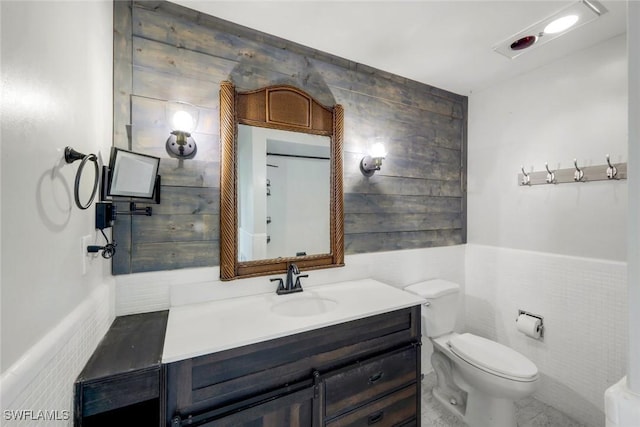 bathroom featuring toilet, tile walls, and vanity