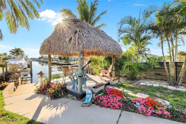 view of patio / terrace featuring boat lift, fence, a dock, and a water view