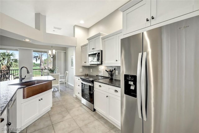 kitchen with dark stone countertops, light tile patterned floors, a sink, stainless steel appliances, and tasteful backsplash