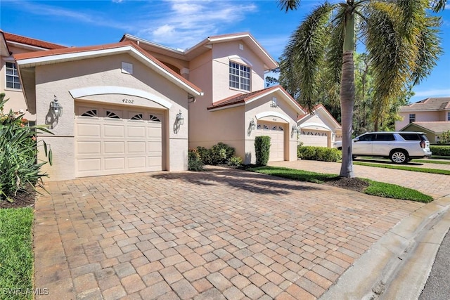 mediterranean / spanish-style house with decorative driveway, an attached garage, and stucco siding