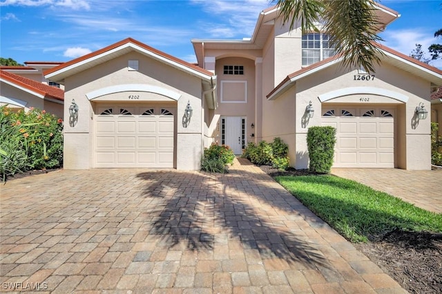 view of front facade featuring stucco siding, decorative driveway, and an attached garage