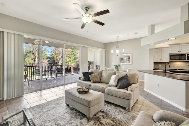 living area featuring light tile patterned floors, ceiling fan with notable chandelier, and baseboards