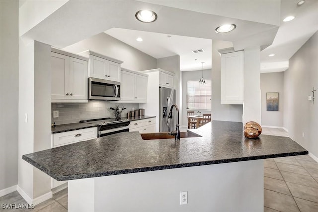 kitchen with visible vents, decorative backsplash, appliances with stainless steel finishes, a peninsula, and white cabinetry