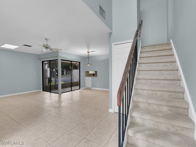 stairway featuring tile patterned flooring, a ceiling fan, visible vents, and baseboards