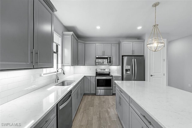 kitchen with a sink, stainless steel appliances, gray cabinetry, and light wood finished floors