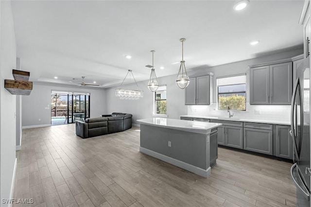 kitchen featuring a kitchen island, tasteful backsplash, gray cabinets, and freestanding refrigerator