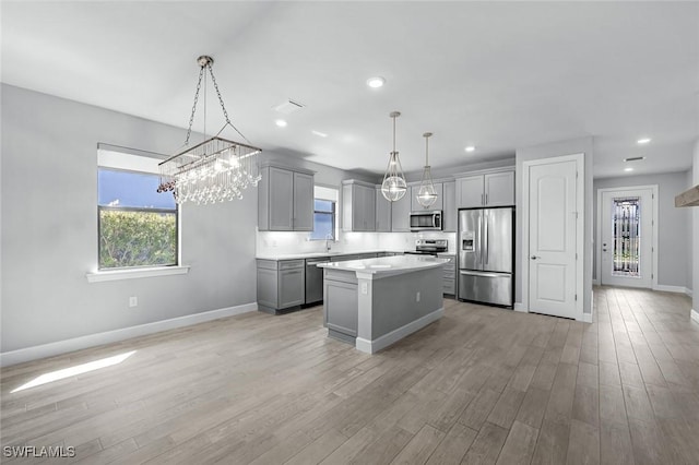 kitchen featuring gray cabinetry, a center island, light wood-style floors, appliances with stainless steel finishes, and light countertops