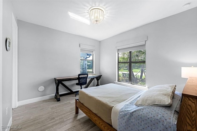 bedroom with wood finished floors, baseboards, and a chandelier