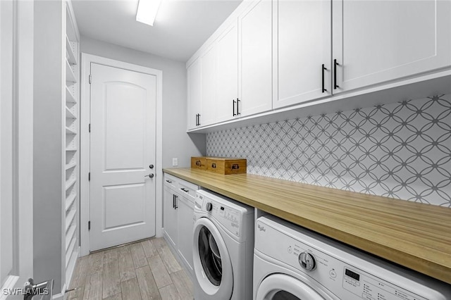 clothes washing area featuring cabinet space, independent washer and dryer, and light wood-style flooring