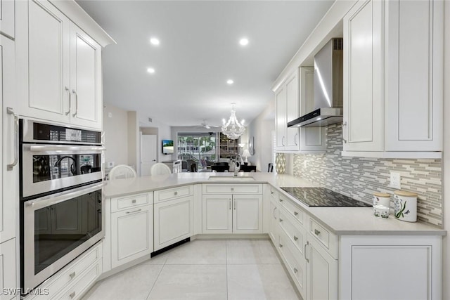 kitchen with stainless steel double oven, a sink, decorative backsplash, black electric stovetop, and wall chimney exhaust hood