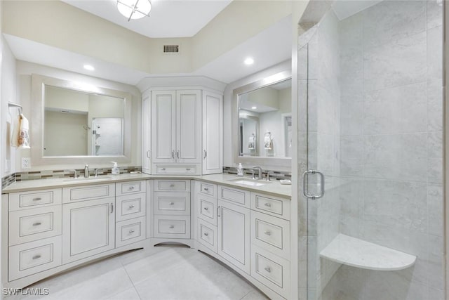 full bath with visible vents, double vanity, a stall shower, tile patterned floors, and a sink