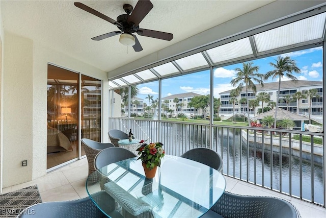 sunroom / solarium featuring a ceiling fan and a water view