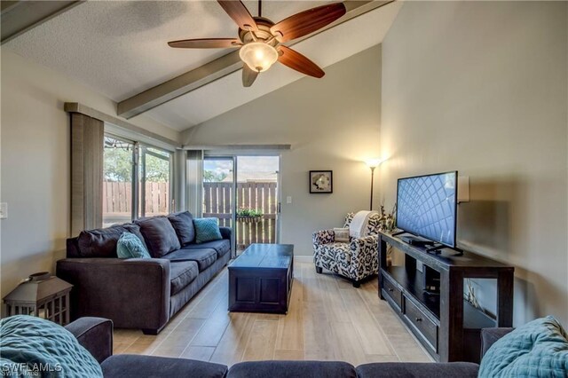 living area with baseboards, light wood-style flooring, vaulted ceiling with beams, ceiling fan, and a textured ceiling