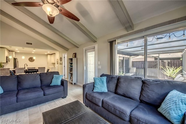 living area featuring lofted ceiling with beams, a ceiling fan, visible vents, and baseboards