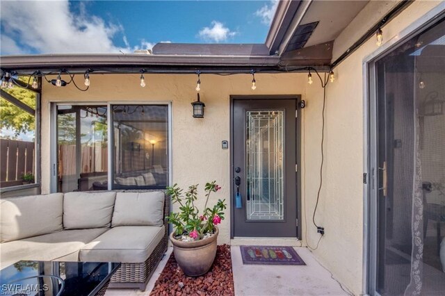 property entrance featuring an outdoor living space, stucco siding, and fence