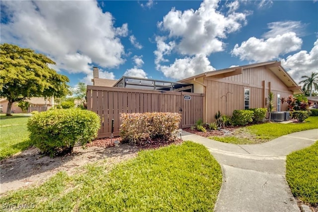 view of side of property with a gate, central AC unit, a yard, and fence