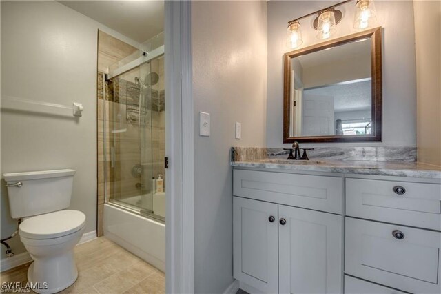 full bath featuring vanity, toilet, baseboards, and bath / shower combo with glass door