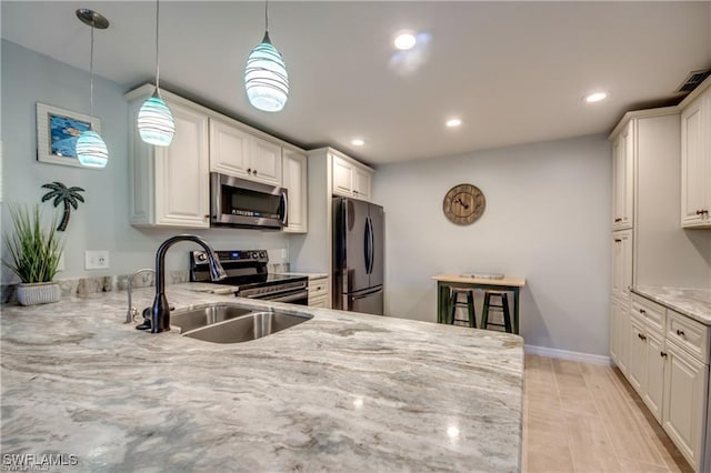 kitchen with pendant lighting, a sink, light stone counters, recessed lighting, and stainless steel appliances