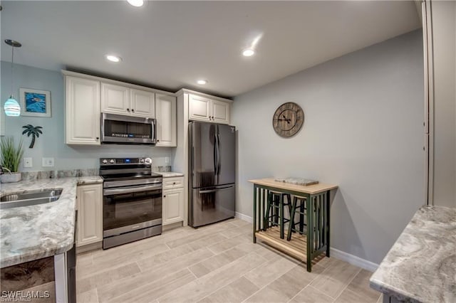 kitchen featuring light stone countertops, recessed lighting, appliances with stainless steel finishes, hanging light fixtures, and a sink