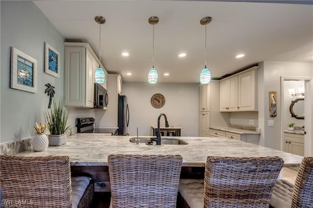 kitchen featuring pendant lighting, a breakfast bar, a sink, appliances with stainless steel finishes, and a peninsula