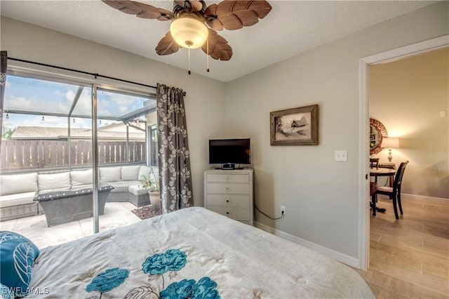 bedroom with ceiling fan, wood finished floors, baseboards, and a textured ceiling