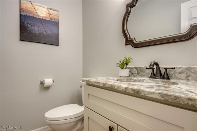 bathroom with baseboards, toilet, and vanity