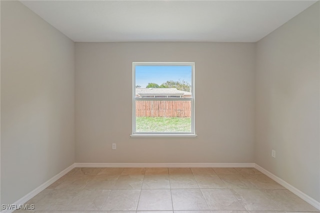 unfurnished room with light tile patterned floors and baseboards