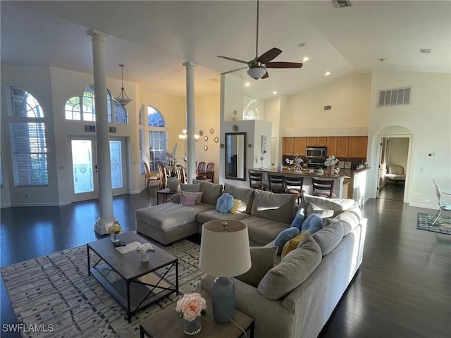 living area with visible vents, ornate columns, high vaulted ceiling, dark wood-style flooring, and ceiling fan