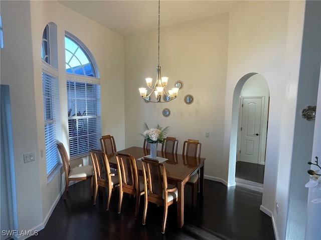 dining room with arched walkways, a notable chandelier, a high ceiling, and dark wood finished floors