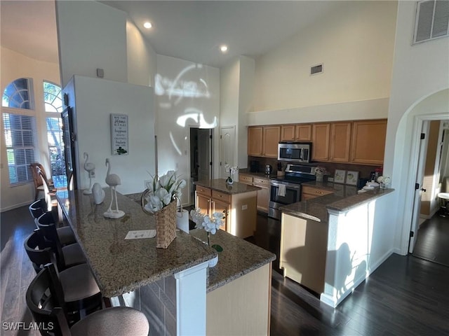 kitchen featuring visible vents, high vaulted ceiling, appliances with stainless steel finishes, and a center island