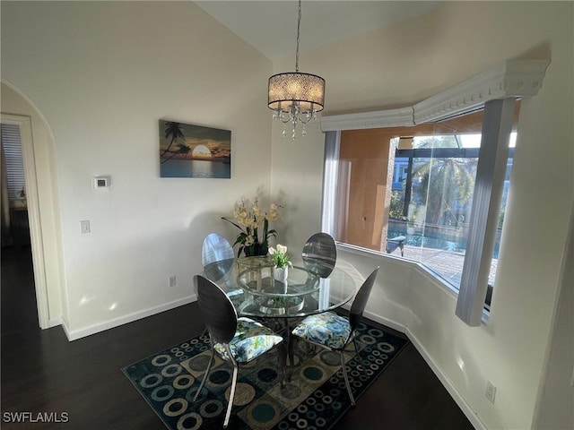 dining area featuring wood finished floors, baseboards, an inviting chandelier, arched walkways, and vaulted ceiling