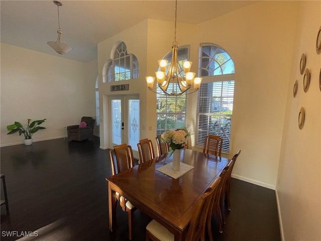 dining area featuring a notable chandelier, a high ceiling, baseboards, and dark wood-style flooring