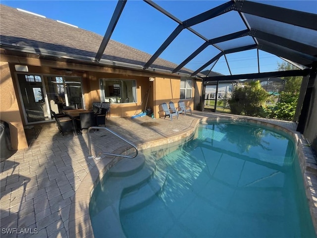 outdoor pool featuring glass enclosure and a patio