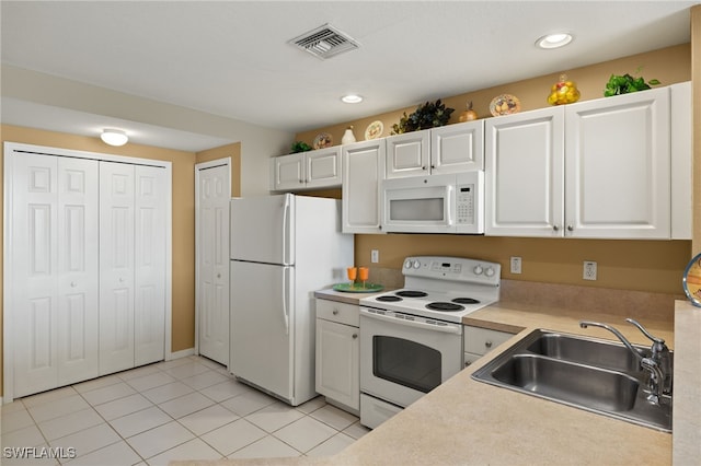 kitchen featuring visible vents, a sink, white appliances, white cabinets, and light countertops