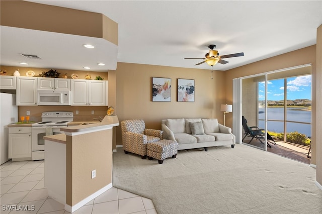 living room featuring light tile patterned floors, visible vents, a water view, and a ceiling fan