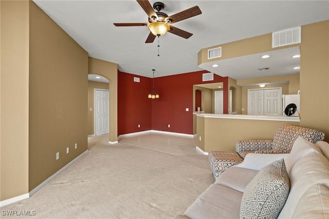 living room with ceiling fan, arched walkways, visible vents, and light carpet