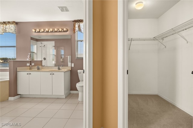 bathroom with visible vents, toilet, double vanity, a stall shower, and a sink