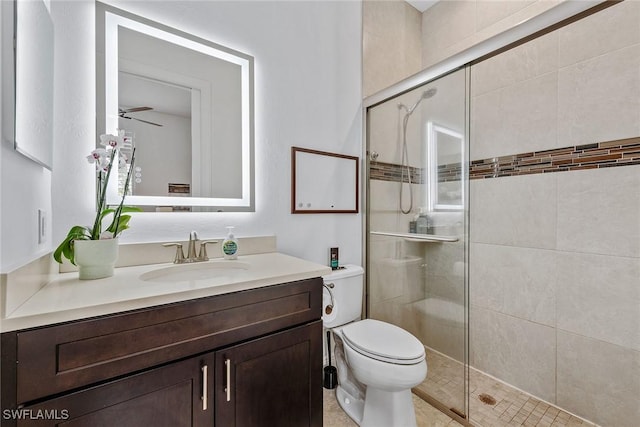 bathroom featuring vanity, a shower stall, toilet, and ceiling fan