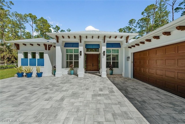 view of front of home featuring stucco siding, an attached garage, and decorative driveway