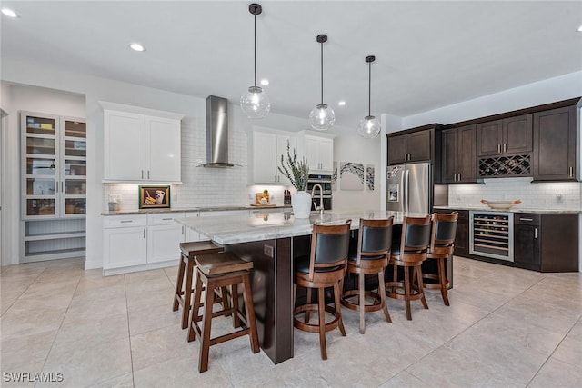 kitchen with a breakfast bar area, beverage cooler, dark brown cabinetry, appliances with stainless steel finishes, and wall chimney exhaust hood