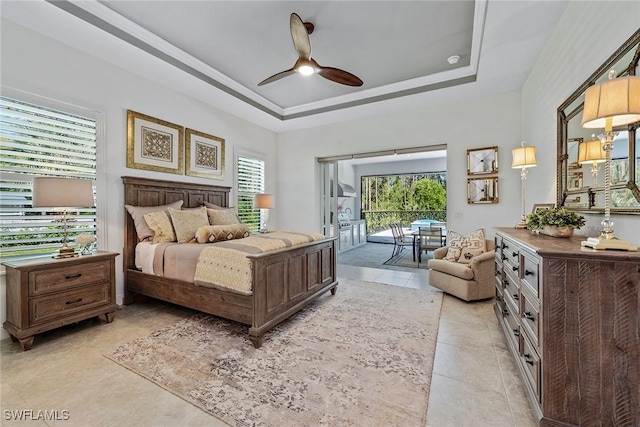 bedroom with a raised ceiling, multiple windows, access to exterior, and ceiling fan