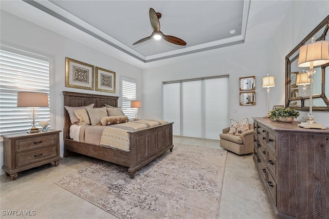 bedroom with a closet, a raised ceiling, and a ceiling fan